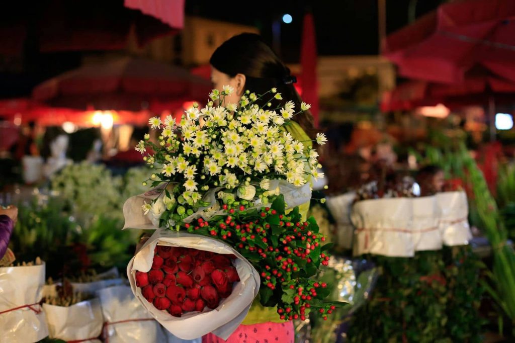 Vendors arranging flowers at Quang Ba Flower Market at night